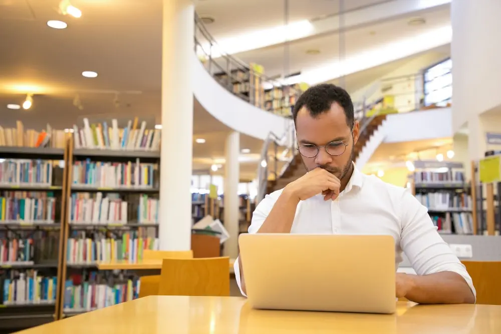 Male student learning on a laptop how to improve academic writing in 2026